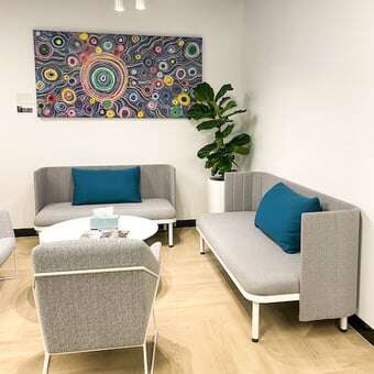 poster green plant grey seats blue pillows round coffee table