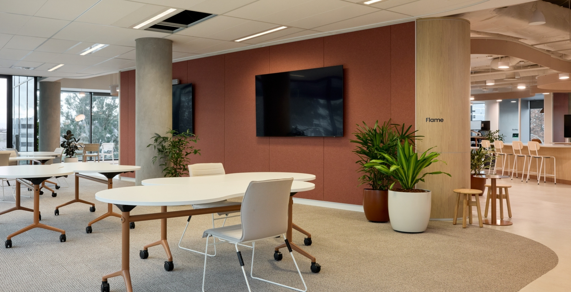 Flexible collaboration space at IRT with modular tables, integrated screens and warm sandstone tones