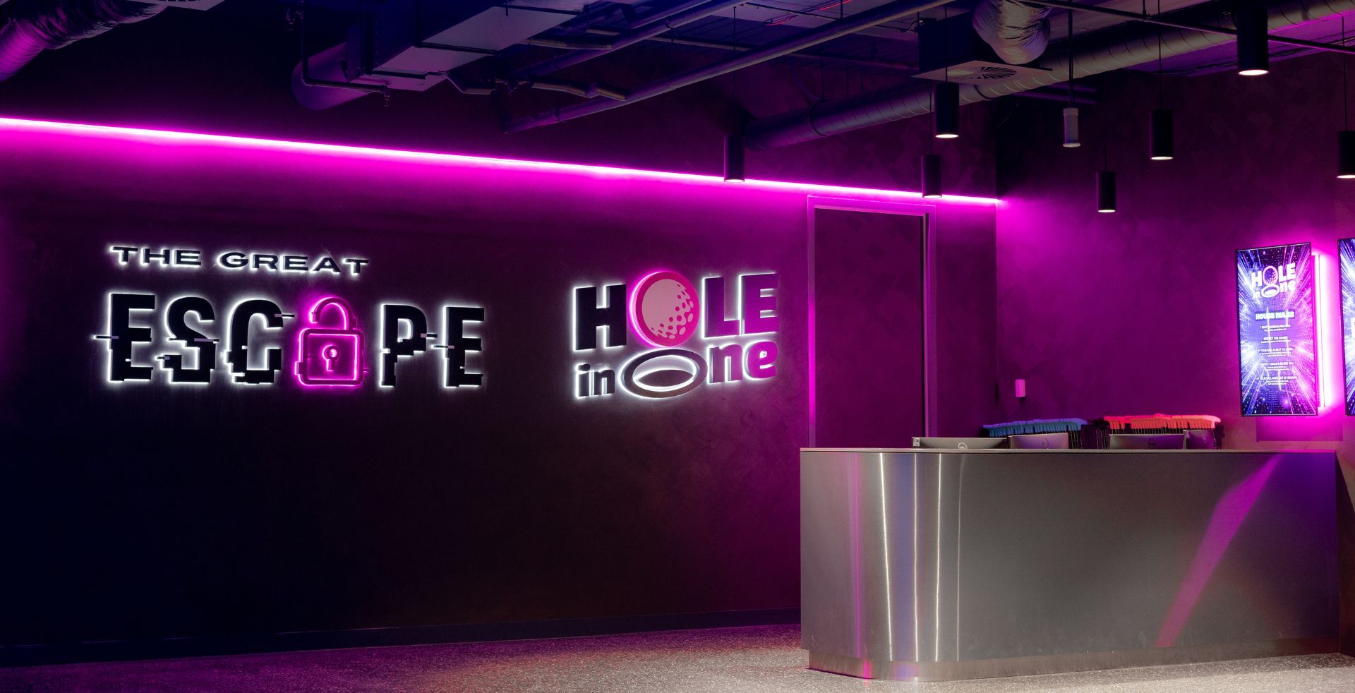 Illuminated Great Escape and Hole in One signage above the arrivals counter, Melbourne venue