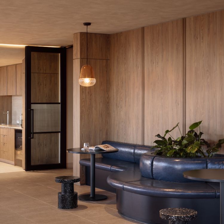Curved navy leather booths and terrazzo stools forming informal meeting space in the Mazzei office