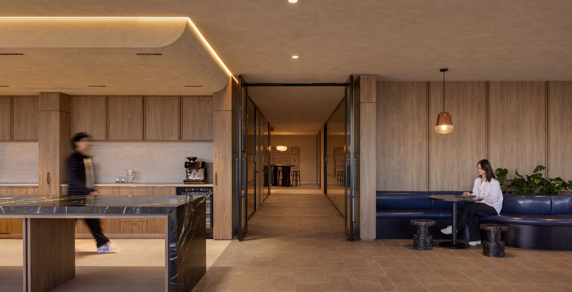 Kitchen, booth seating and glazed corridor connecting social and meeting zones in the Mazzei workplace