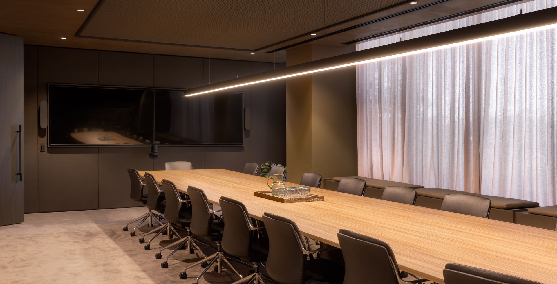 Boardroom with long timber table and dual screens at Mazzei's head office, an Amicus fitout