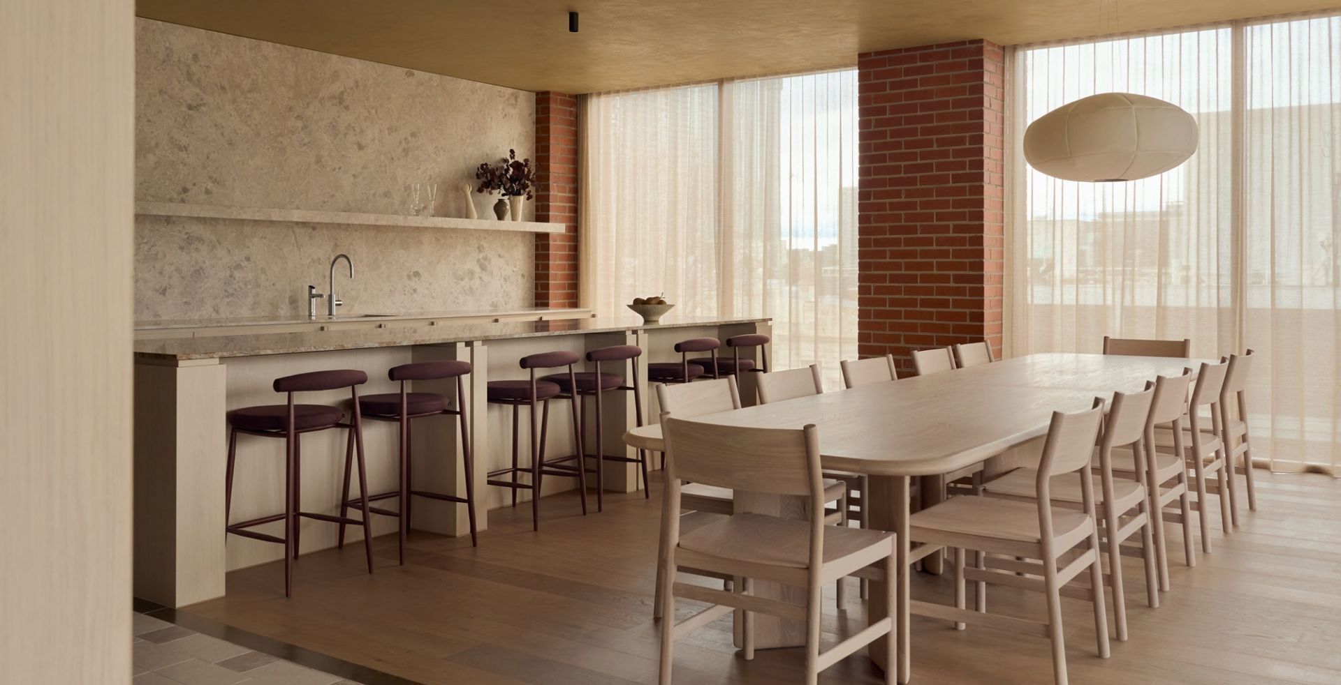 Dining and kitchen area at Lowe Living's headquarters, with a stone splashback and brick column