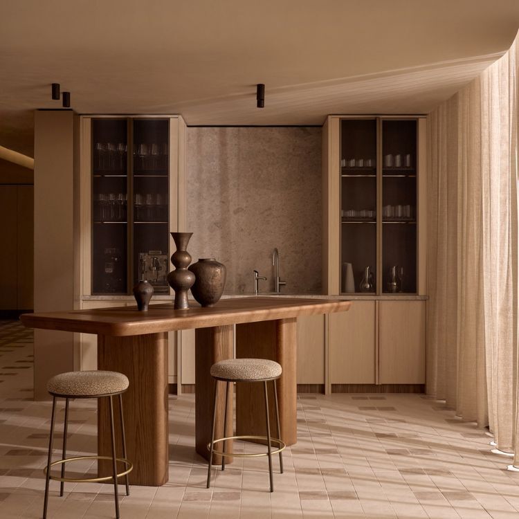 Timber bar table and stools before glass-fronted cabinets in Lowe Living's Made For-designed workplace