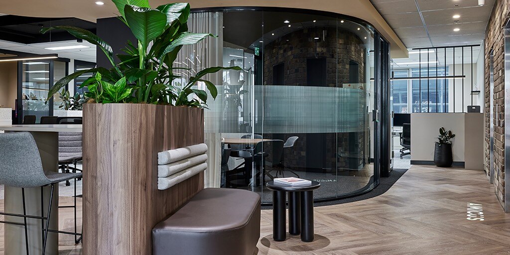 Modern office interior featuring plants, stylish seating, and glass meeting room, showcasing Amicus Sydney's design.