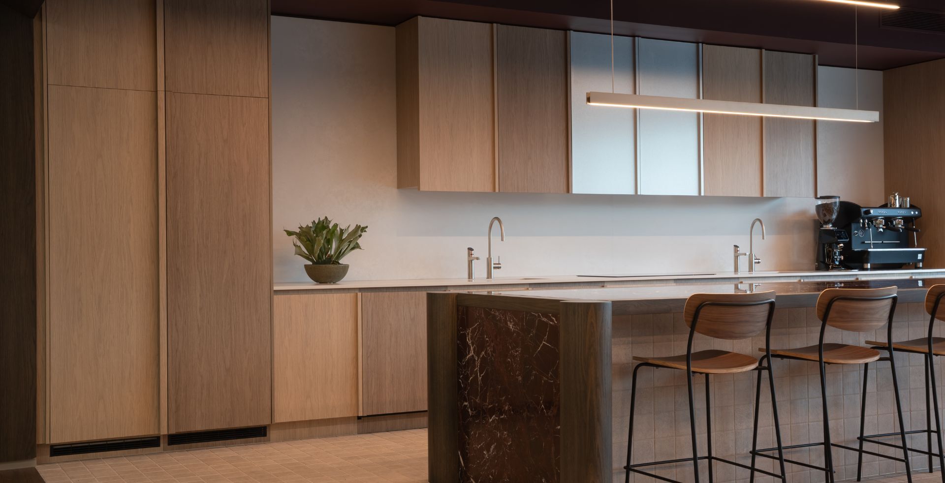 Kitchen-style breakout area with timber joinery and stone island
