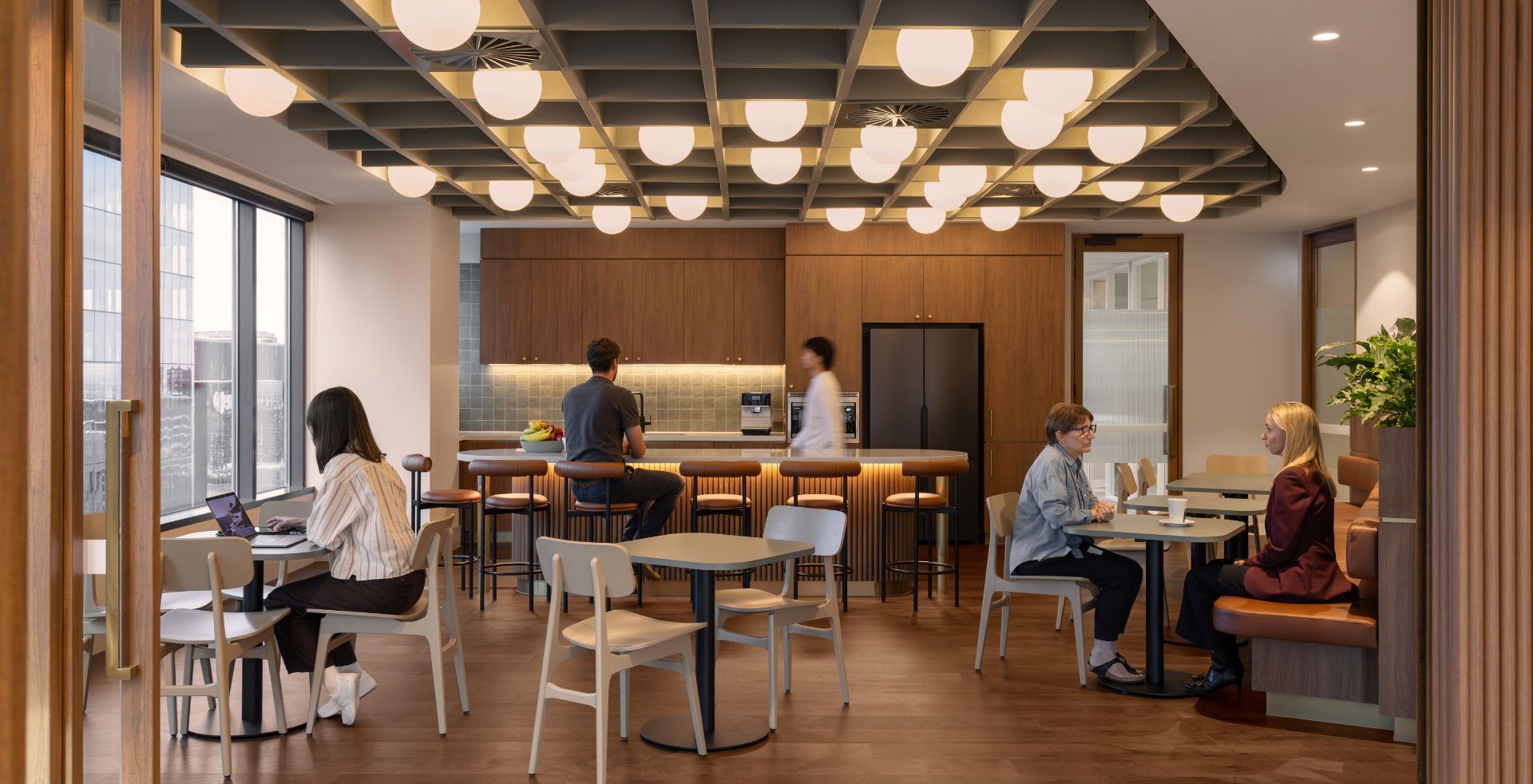 Breakout and kitchen space with timber finishes, bar seating and feature lighting in a Melbourne office fitout.