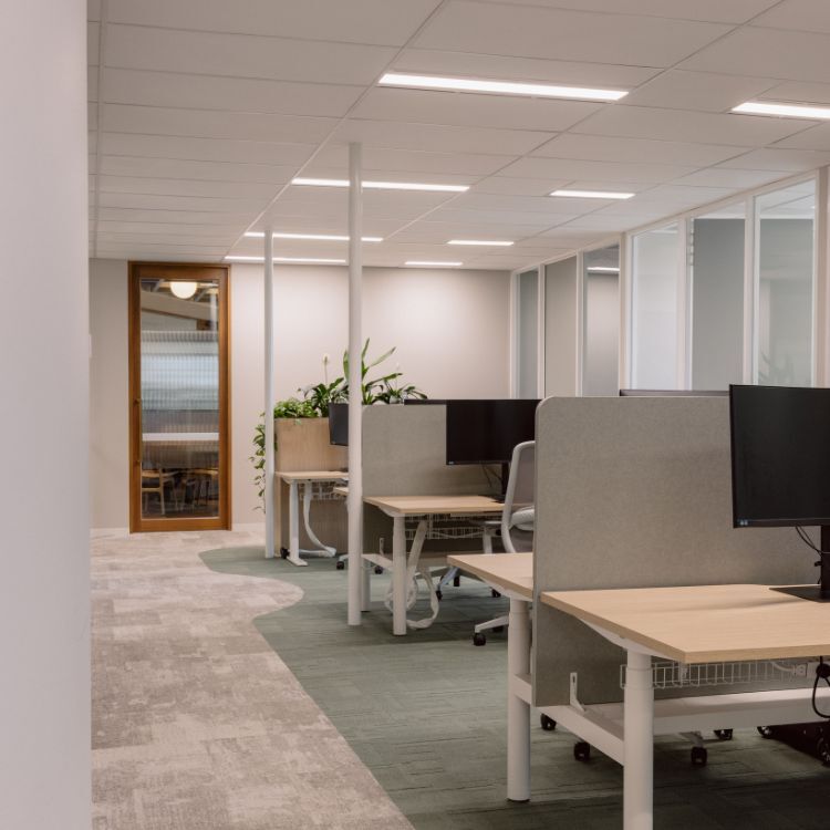 Open workspace with desks and privacy screens in Gilchrist Connell’s Melbourne office.