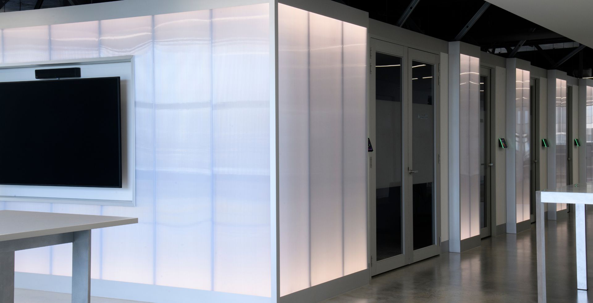 Backlit wall panels and glass meeting rooms within Akaysha Energy’s modern Melbourne workplace.