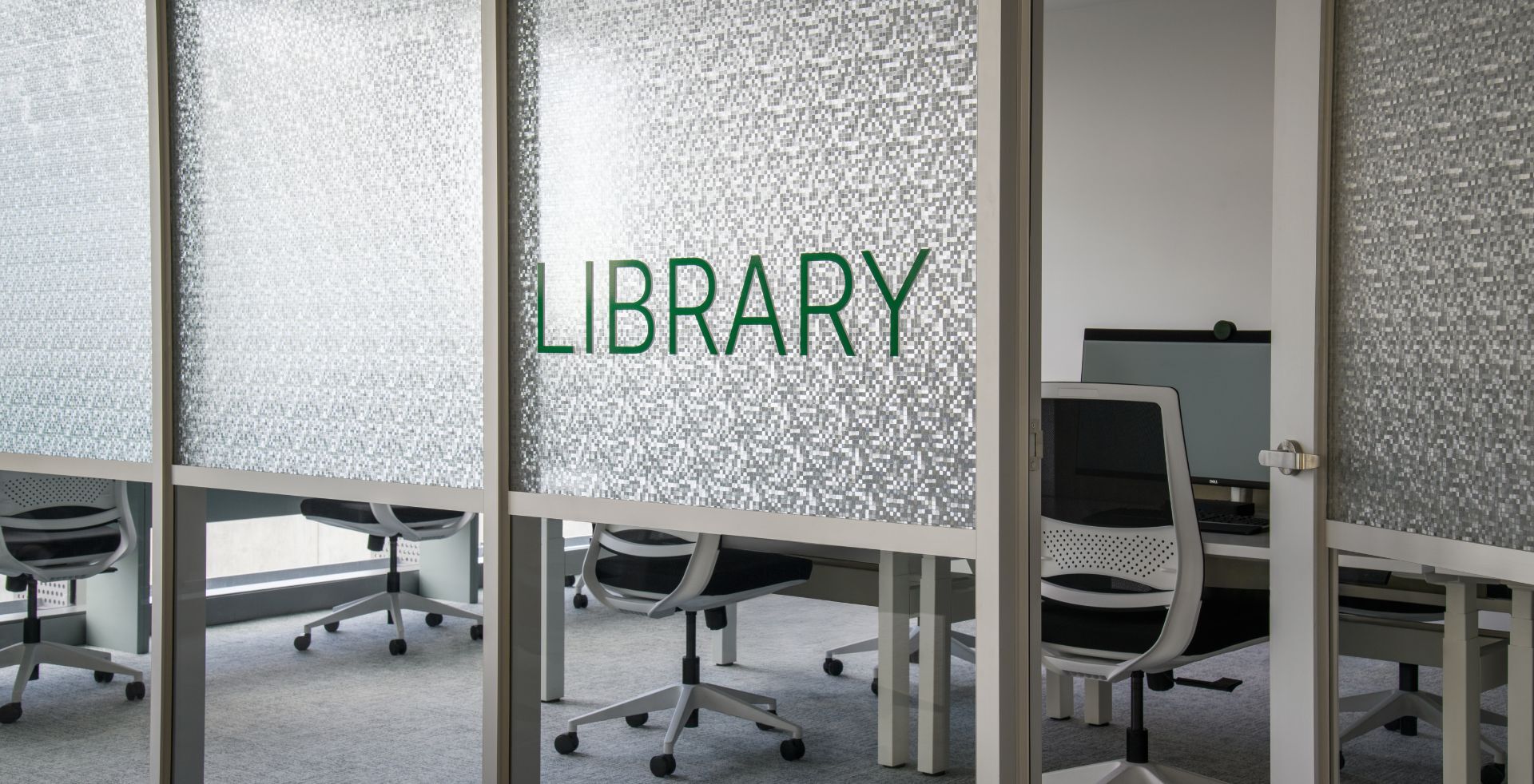 Quiet library workspace with textured glass partitioned and workstation desks