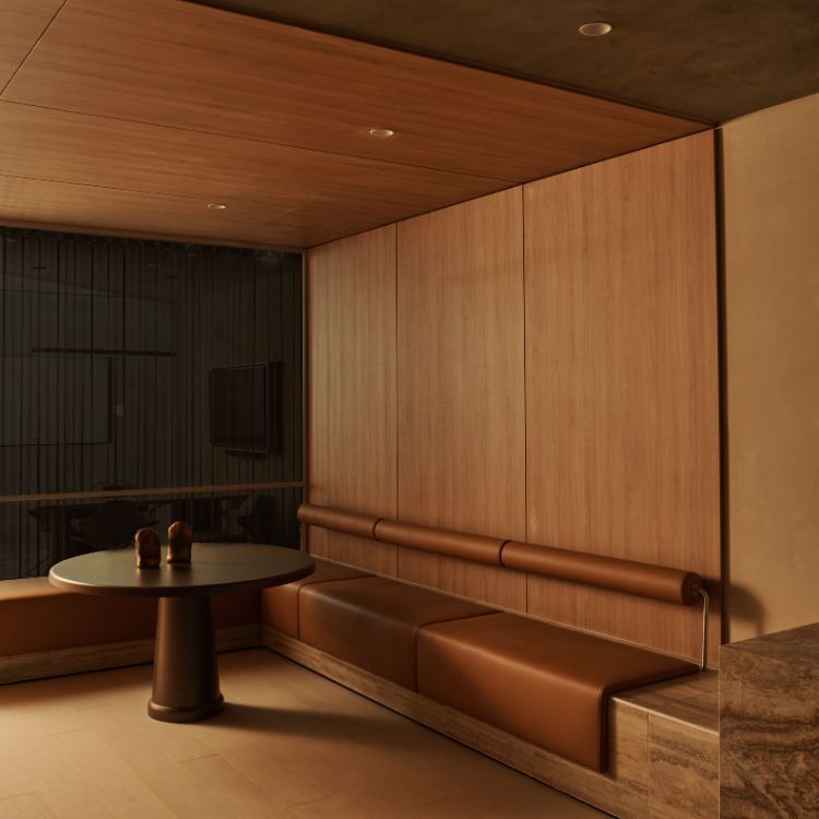 Warm, timber-lined workplace lounge with built-in leather banquette seating, a round table and stone detailing, creating a calm, refined meeting space with soft lighting.