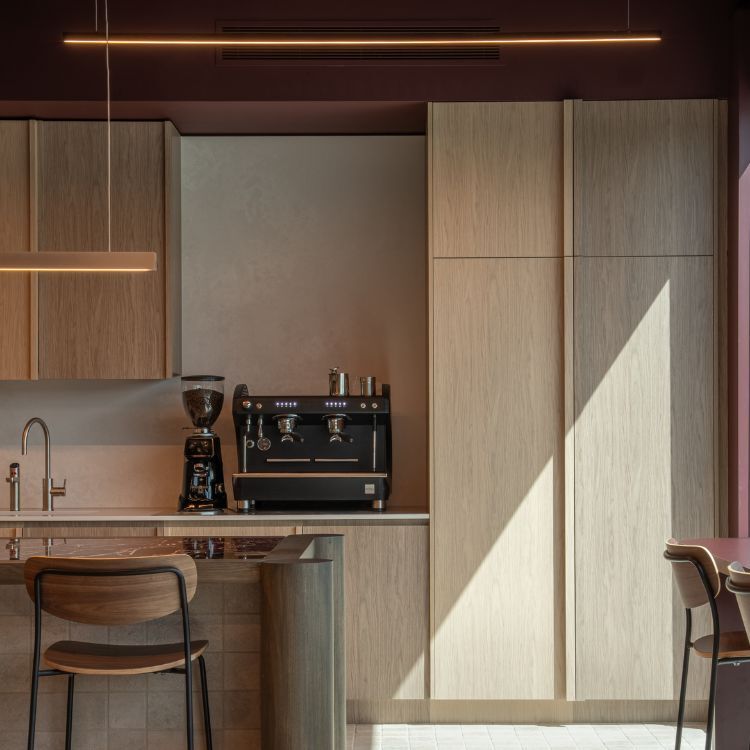 Residential-style kitchenette with timber cabinetry, stone benchtops and bar seating in Carter Grange office.