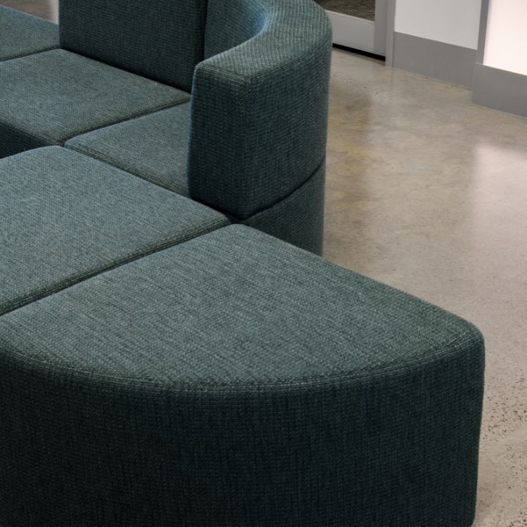 Curved upholstered lounge seating in a modern office space with polished concrete flooring.