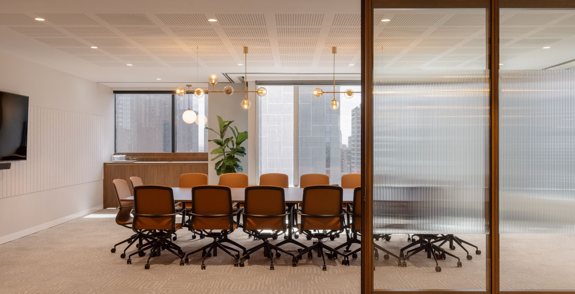 Meeting room with warm timber finishes, leather seating and feature pendant lighting.
