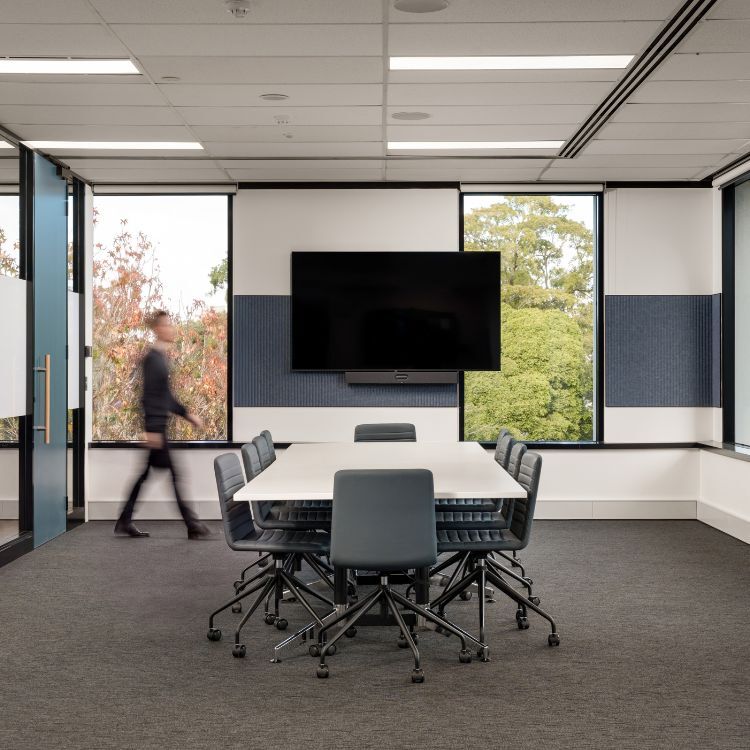 Meeting room featuring a white board table, grey chairs, and a wall-mounted display screen for Diabetes Australia's office