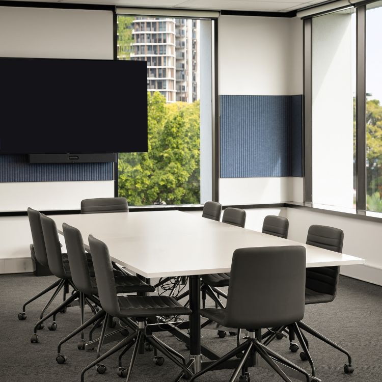 Conference room featuring a white board table, black rolling chairs, and a large wall-mounted screen