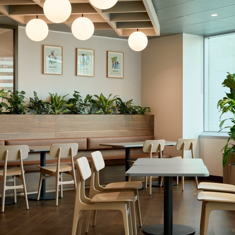 Office breakout and kitchen space featuring timber banquette seating, dining tables, and hanging globe pendant lights in Gilchrist Connell's office.