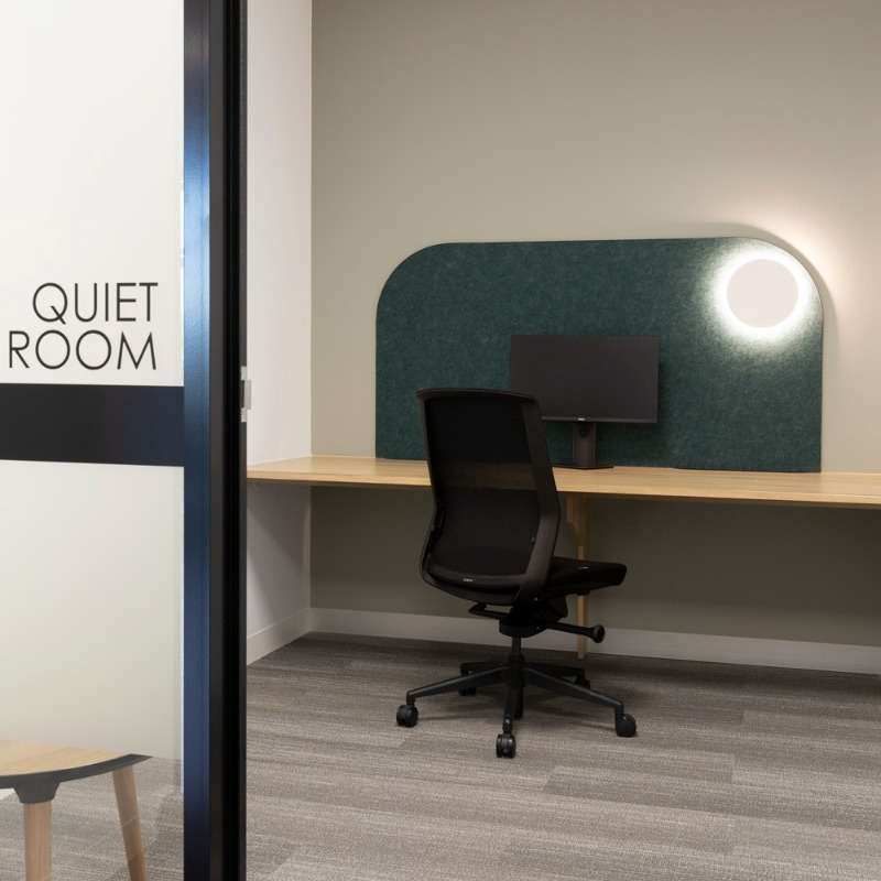 A room with the words 'QUIET ROOM' printed on the glass of the entrance way with a monitor, office chair and table.