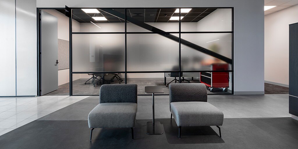 A contemporary office featuring a glass wall and stylish chairs, creating an open and inviting workspace atmosphere.