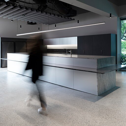 Woman walking past elegant kitchen counter.