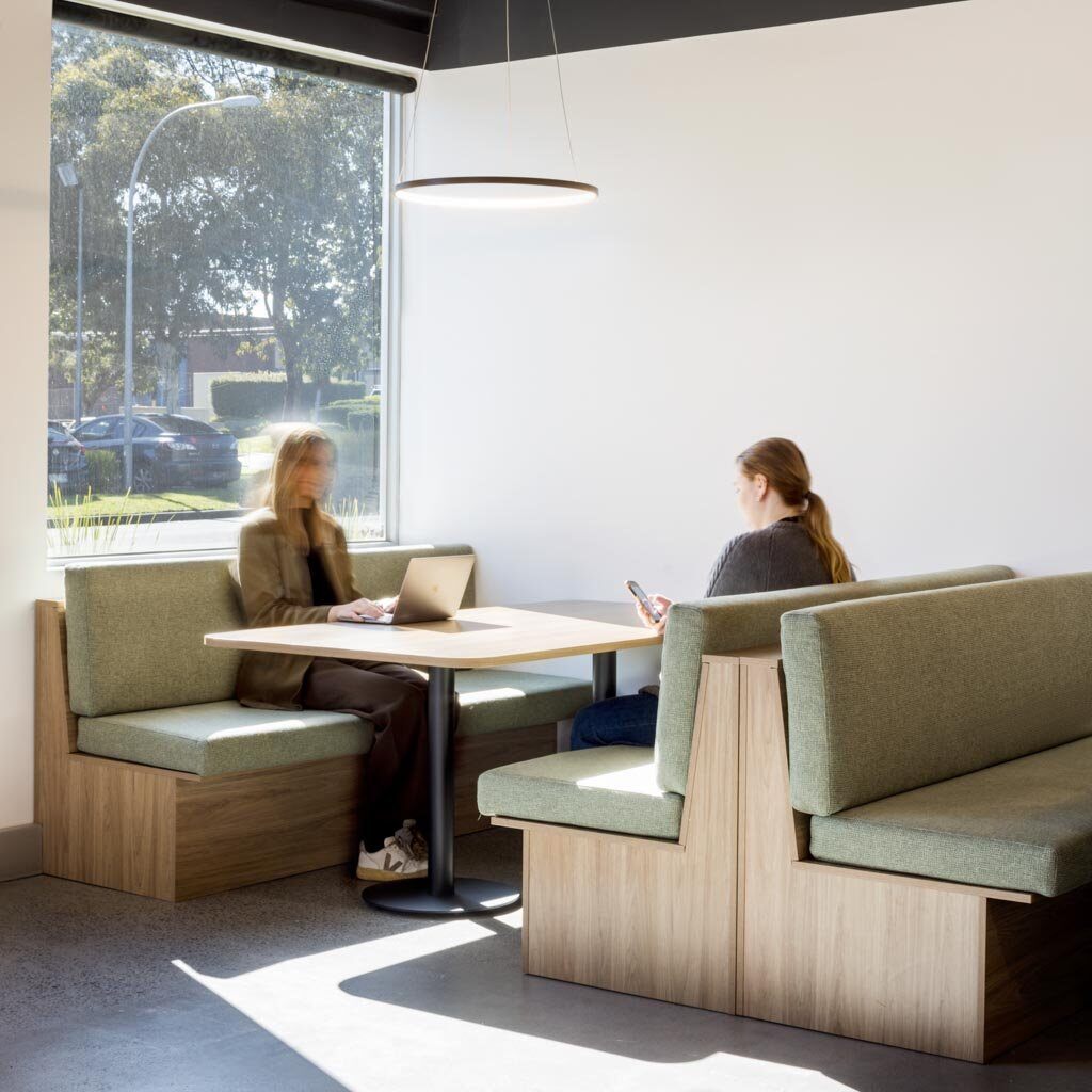 Two women sitting across each from each other in a sleek, modern booth.