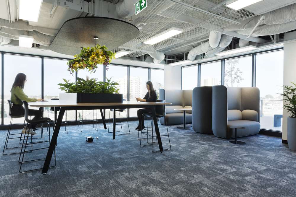 Two women working at tall table coupled with bar chairs, greenery in the middle of the table and great views.